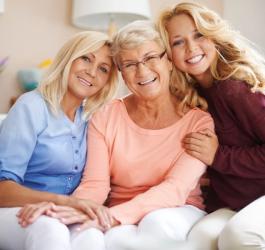 Babcia, mama i córka siedzą na kanapie i pozują do zdjęcia.