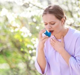Kobieta z objawami astmy alergicznej korzysta z inhalatora.