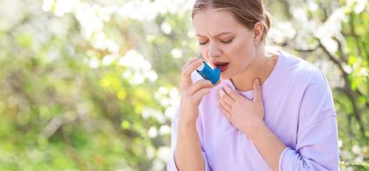 Kobieta z objawami astmy alergicznej korzysta z inhalatora.
