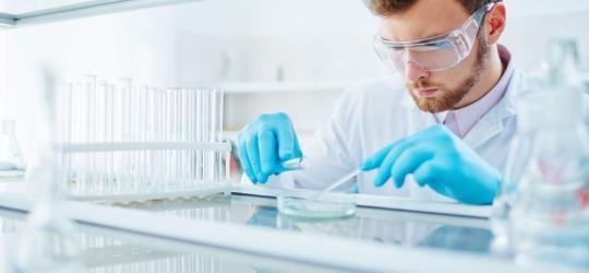Laborant w okularach ochronnych i rękawiczkach, wykonuje swoją pracę.