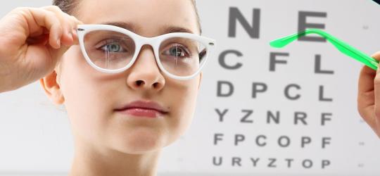 Dziewczynka podczas badania wzroku i przymiarki okularów korekcyjnych.