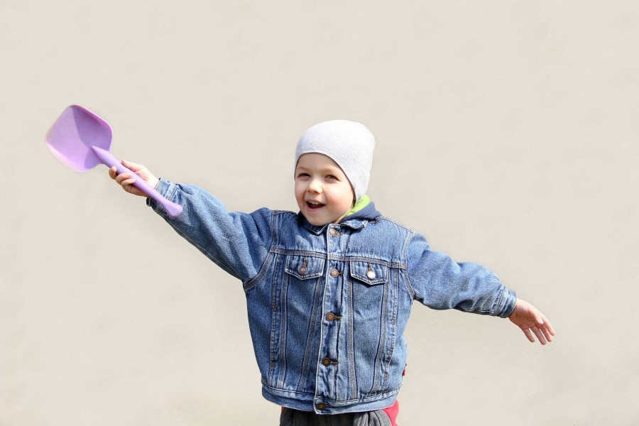 Dziecko z łopatką w ręku, gotowe do zabawy w piaskownicy.