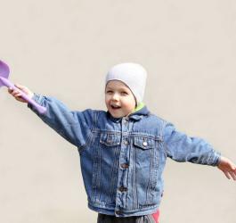 Dziecko z łopatką w ręku, gotowe do zabawy w piaskownicy.