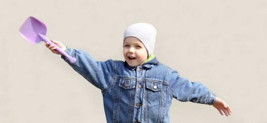 Dziecko z łopatką w ręku, gotowe do zabawy w piaskownicy.