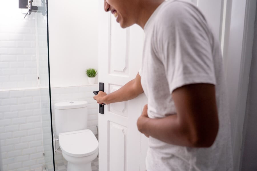 Mężczyzna wchodzi do toalety, męczy go biegunka po jedzeniu.