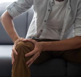 Mężczyzna trzyma się za kolano, które boli w spoczynku.