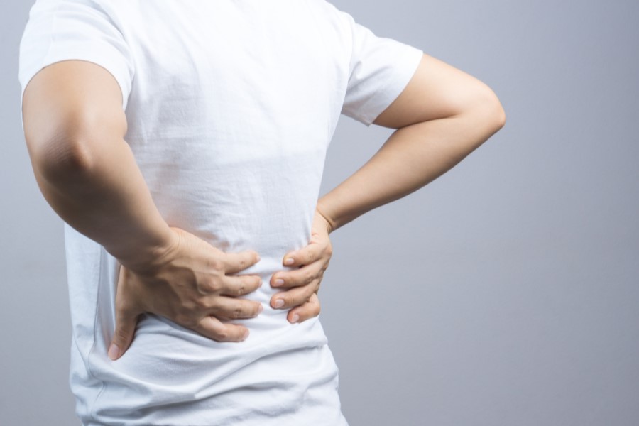 Mężczyzna trzyma się za plecy, cierpi na bóle kręgosłupa.