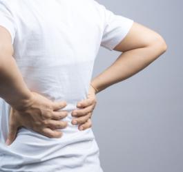 Mężczyzna trzyma się za plecy, cierpi na bóle kręgosłupa.