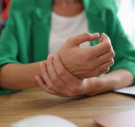 Kobieta przerywa pracę, boli ją nadgarstek.