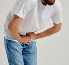 Mężczyzna odczuwa ból w pachwinie, schyla się z bólu.