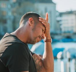 Mężczyzna przykłada dłoń do czoła. Boli go głowa.