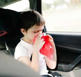 Chłopiec w samochodzie próbuje poradzić sobie z objawami choroby lokomocyjnej.