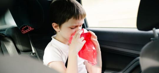 Chłopiec w samochodzie próbuje poradzić sobie z objawami choroby lokomocyjnej.