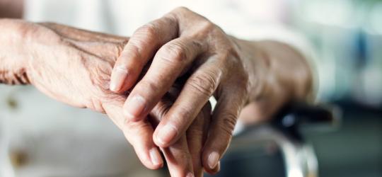 Dłonie starszej kobiety chorującej na chorobę Parkinsona.