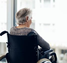 Starsza osoba na wózku inwalidzkim dotknięta chorobą otępienną.