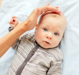 Mama dotyka główki dziecka tam, gdzie znajduje się ciemiączko.