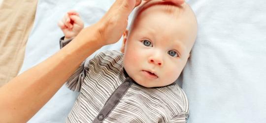 Mama dotyka główki dziecka tam, gdzie znajduje się ciemiączko.