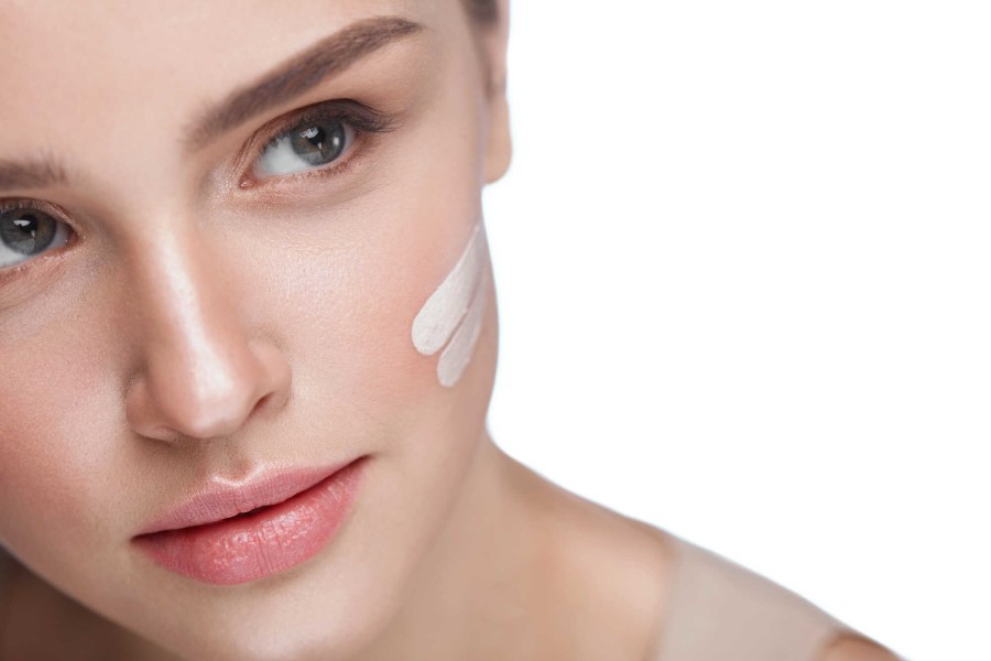 Kobieta smaruje policzek kremem z filtrem SPF.