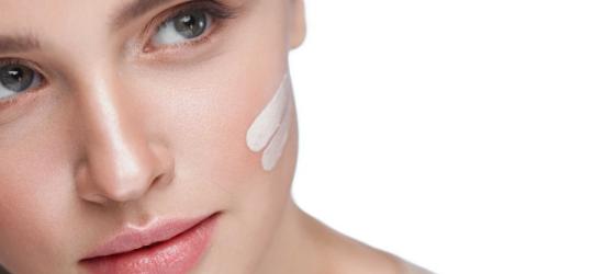 Kobieta smaruje policzek kremem z filtrem SPF.