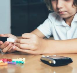 Dziecko z cukrzycą sprawdza poziom glukozy przy pomocy glukometru.