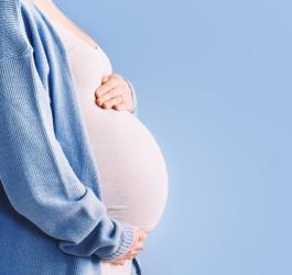 Ciężarna kobieta trzyma się za ciążowy brzuszek.