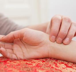 Mężczyzna mierzy kobiecie puls na nadgarstku. Sprawdza, czy ma wysoki puls.