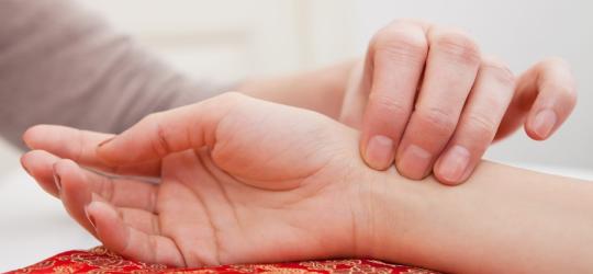 Mężczyzna mierzy kobiecie puls na nadgarstku. Sprawdza, czy ma wysoki puls.