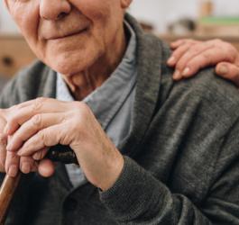 Starszy mężczyzna opiera się o drewnianą laskę.