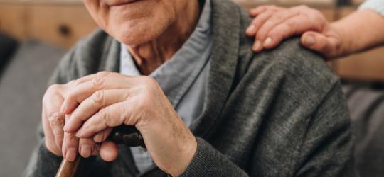 Starszy mężczyzna opiera się o drewnianą laskę.