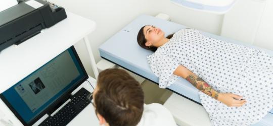Lekarz wykonuje densytometrię u pacjentki.