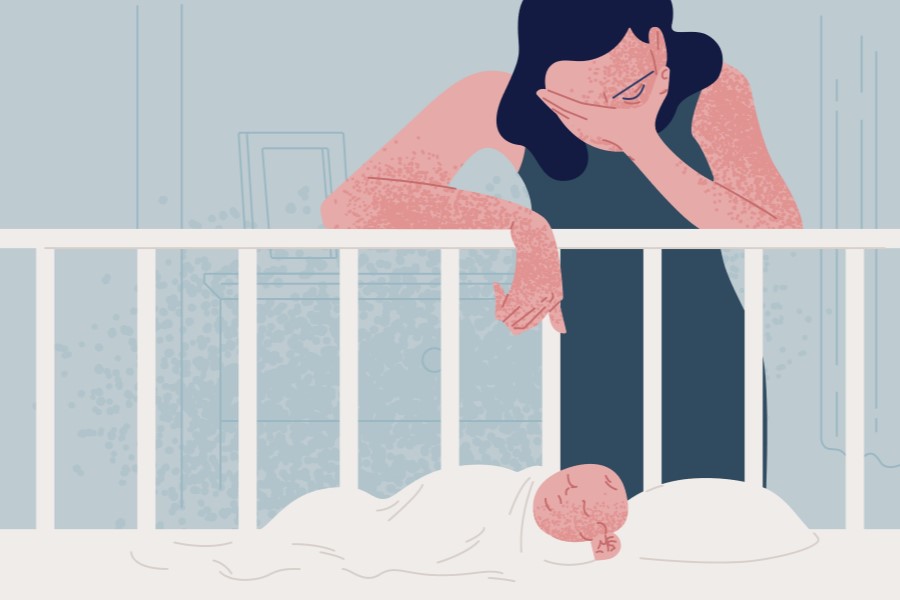 Kobieta z depresją poporodową stoi zrezygnowana nad łóżeczkiem dziecięcym, w którym leży niemowlę.