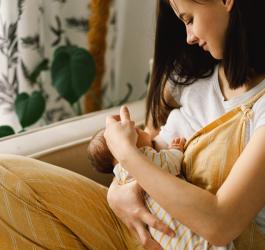 Młoda mama karmi piersią noworodka.