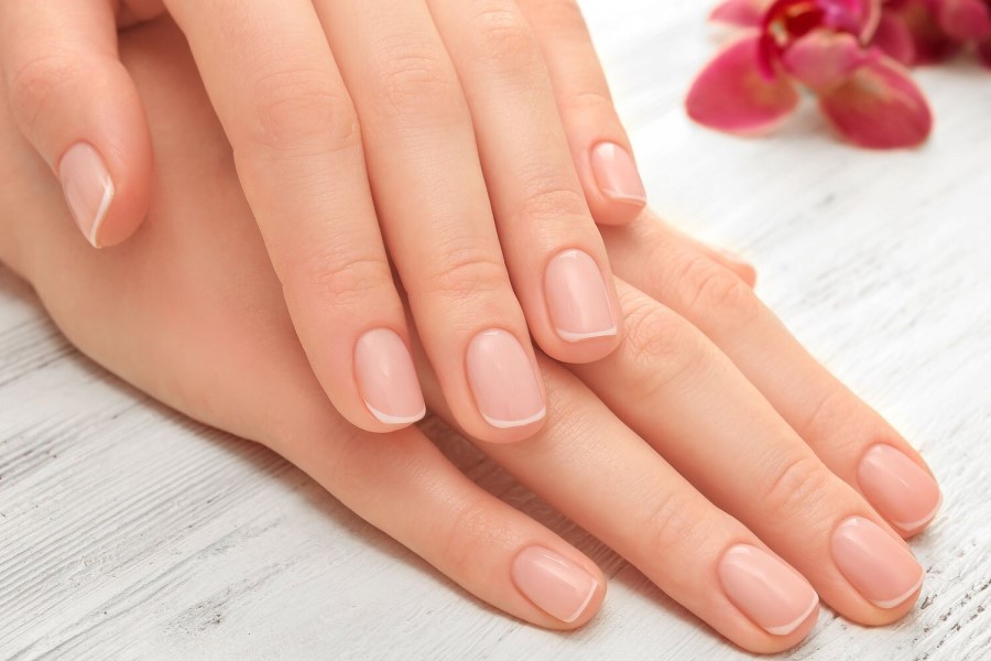 Zadbane, kobiece dłonie na jasnym tle.