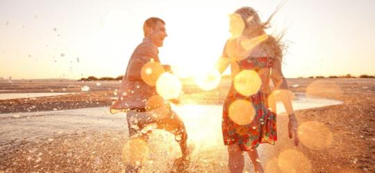 Para młodych ludzi bawi się nad brzegiem morza.