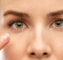 Kobieta wskazuje na swoje prawe oko, dokucza jej drganie powieki dolnej.