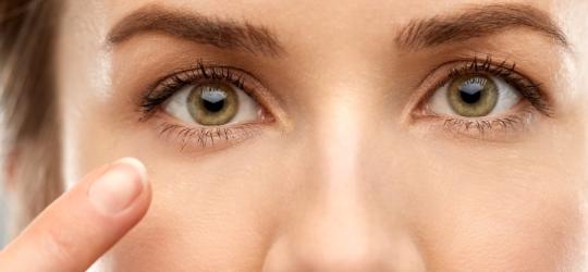 Kobieta wskazuje na swoje prawe oko, dokucza jej drganie powieki dolnej.