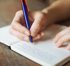 Osoba w trakcie ręcznego pisania w zeszycie.