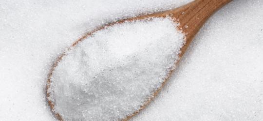 Drewniana łyżeczka na tle erytrytolu.