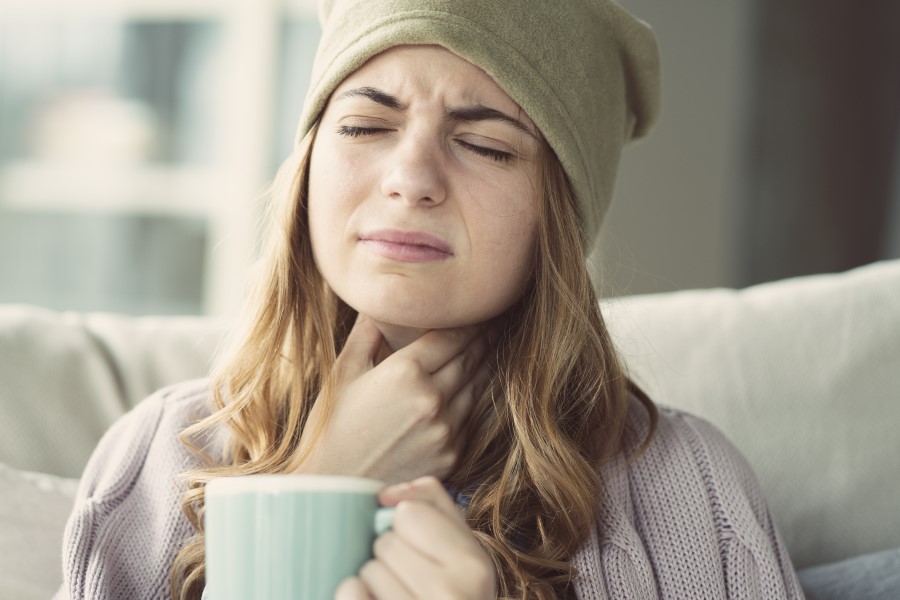 Kobiecie doskwiera flegma w gardle, trzyma się dłonią za szyję.