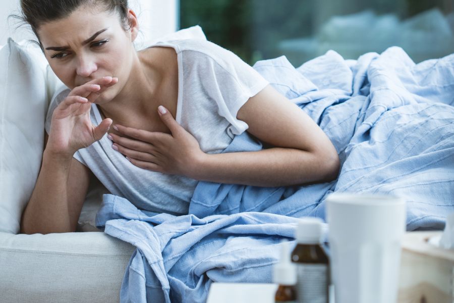 Młoda kobieta leży w łóżku, źle się czuje z powodu gorączki reumatycznej.