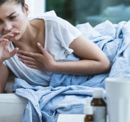 Młoda kobieta leży w łóżku, źle się czuje z powodu gorączki reumatycznej.