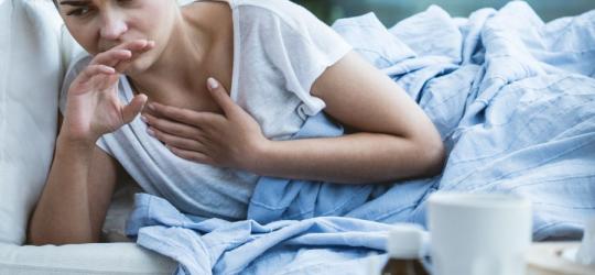 Młoda kobieta leży w łóżku, źle się czuje z powodu gorączki reumatycznej.