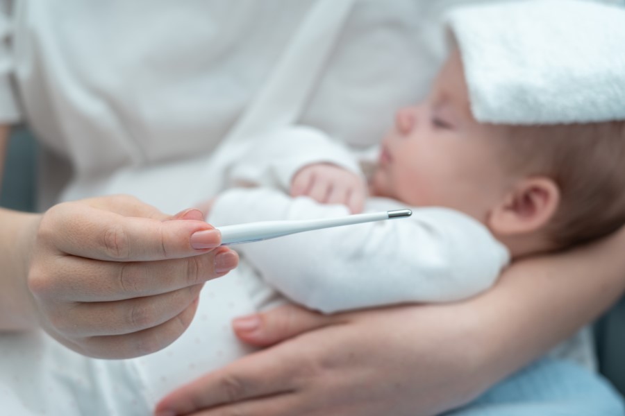 Mama mierzy temperaturę dziecku, które choruje na gorączkę trzydniową.