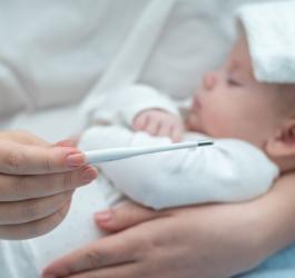 Mama mierzy temperaturę dziecku, które choruje na gorączkę trzydniową.