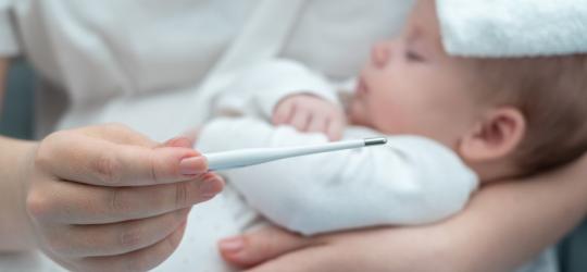 Mama mierzy temperaturę dziecku, które choruje na gorączkę trzydniową.
