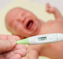 Rodzic mierzy temperaturę u płaczącego noworodka.