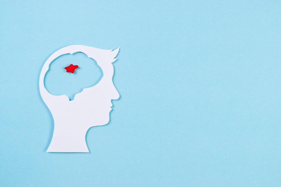 Wycięta z papieru głowa człowieka. W obszarze mózgu zaznaczony na czerwono guz mózgu.