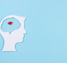 Wycięta z papieru głowa człowieka. W obszarze mózgu zaznaczony na czerwono guz mózgu.