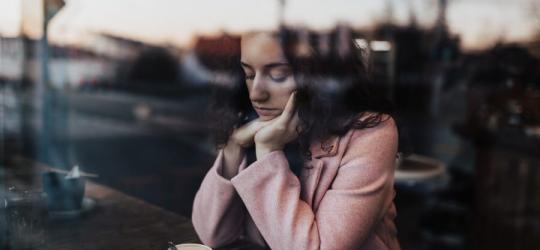 Zmartwiona kobieta pije kawę w kawiarni.