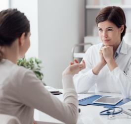 Kobieta podczas konsultacji u lekarki, która podejrzewa u pacjentki hiperandrogenizm.